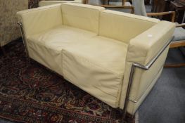 In the manner of Le Corbusier, a cream leather upholstered and chrome framed two seater settee.