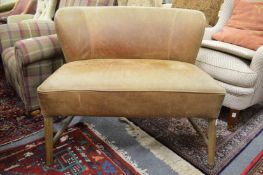An Oka tan leather upholstered small settee on ash supports.