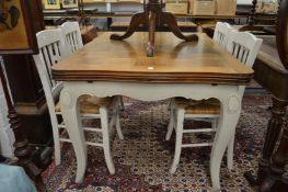 A French fruit wood and painted drawer leaf dining table with four rush seated chairs.