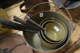 A brass preserve pan and four similar saucepans.