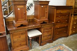 A modern hardwood bedroom suite comprising large chest of drawers, kneehole dressing table with