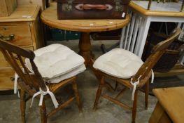 A pine circular kitchen table and two chairs.