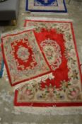 A red ground floral decorated rug and a similar smaller rug 5' x 3' and 3' x 2'.