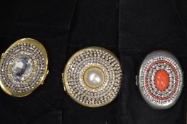 Three decorative compacts.