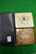 A tin box containing coins together with a leather purse.