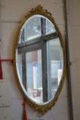 A gilt framed oval mirror.