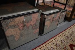 A graduated set of three trunks decorated with maps of the world.