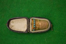 A leather cased gilt metal and turquoise set thimble, possibly gold but untested.