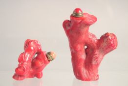 TWO CHINESE RED CORAL SNUFF BOTTLES & STOPPERS, each carved in the form of Budai and a tree trunk,