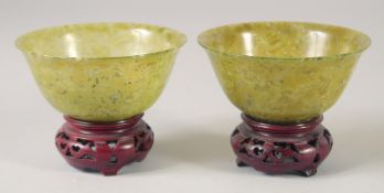 A PAIR OF JADE BOWLS, on hardwood stands, bowls 10cm diameter.