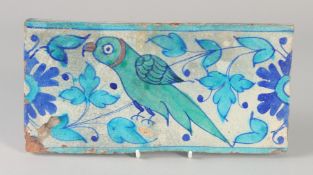A FINE EARLY 19TH CENTURY MUGHAL INDIAN MULTAN TILE, painted with a green parrot, 28.5cm x 14.5cm.