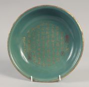 A CHINESE CELADON GLAZE DISH, with carved gilt characters, 23.5cm diameter.