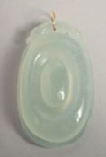 AN ICY JADE PENDANT with gold ring.