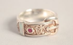A SILVER OPAL AND RUBY BUCKLE RING.
