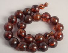 AN AMBER NECKLACE with twenty one ball beads. 15ins long.