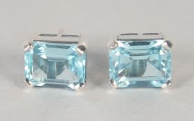 A PAIR OF SILVER EMERALD CUT BLUE TOPAZ STUDS.