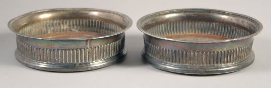 A PAIR OF GEORGE III CIRCULAR PLATED WINE COASTERS and turned wood bases. 5.25ins diameter.