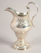 A LARGE III SILVER CREAM JUG with repousse decoration. London, 1768.