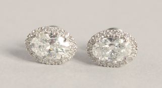A SUPERB PAIR OF 18CT WHITE GOLD OVAL DIAMOND SET EARRINGS, the central diamonds 1.03ct to 1.02ct.