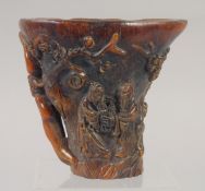 A GOOD CHINESE CARVED HORN LIBATION CUP carved with lotus and figures. 5.5ins.