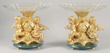 A VERY GOOD PAIR OF GILT BRONZE COMPORTS with gilt bowls and cupid supports.
