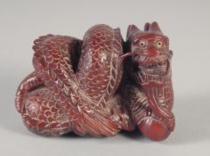 A CARVED WOOD DRAGON NETSUKE, signed. 2ins long.