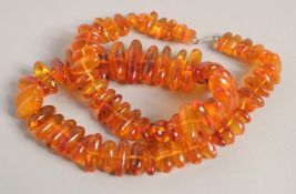AN AMBER NECKLACE with graduated beads. 24ins long.