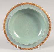 A CHINESE CELADON PETAL FORM DISH with incised gilt characters to the base. 20cm diameter.