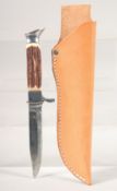 A KNIFE, with thumb guard and antler handle, in a leather sheath, 8