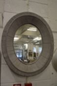 A grey painted oval wall mirror.