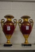A pair of gilt decorated twin handled urn shaped vases.