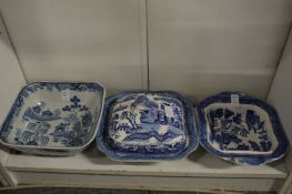 A willow pattern vegetable dish and cover and two other similar dishes.