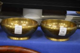 A pair of heavy brass bowls.
