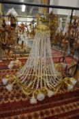 A large brass and cut crystal chandelier with scrolling branches having frosted glass shades.