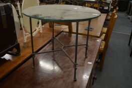 A circular glass coffee table with wrought iron base.