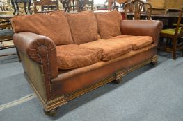 An oak framed leather cloth and upholstered three seater settee.