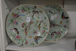 A pair of Chinese celadon ground circular dishes painted with birds and flowers (both repaired).