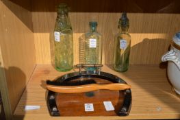 A horseshoe shaped crumb tray and brush and three old bottles.