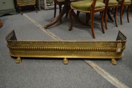 A Regency pierced brass fender with pierced decoration supported on three cast brass claw feet, 3'