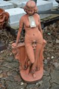 A terracotta coloured garden sculpture of a classical standing female figure.