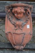 A terracotta coloured garden wall font with cherub face.