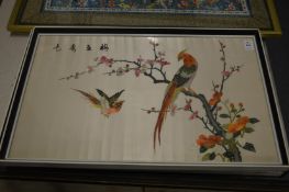 A pair of colourful Chinese embroidered pictures depicting exotic birds on branches.