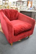 A red velvet upholstered modern deep armchair.