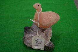 A rose quartz carved bird on an amethyst base.