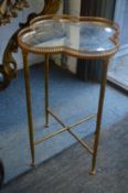 A gilt metal quatrefoil shaped occasional table with mirrored top.