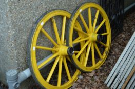 A pair of yellow painted wagon wheels.