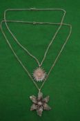 Two filigree silver flower head pendants with chains.