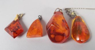FOUR VARIOUS AMBER PENDANTS, 28gms.