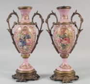 A PAIR OF SEVRES STYLE PINK PORCELAIN TWO HANDLED URNS with ormolu mounts, with panels of flowers.