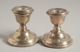 A PAIR OF SILVER SQUAT CANDLESTICKS on loaded bases. 2.25ins high.